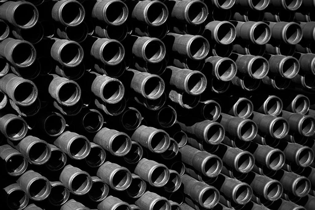 Black and white artistic photo showcasing a pattern of industrial pipes forming a repetitive structure.