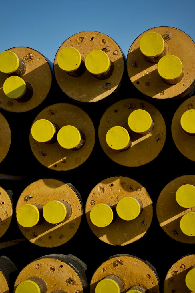 Close-up of stacked yellow industrial pipes with visible rust against a blue sky. Industrial theme.